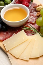 Photo of Snack set with delicious Parmesan cheese on board, closeup