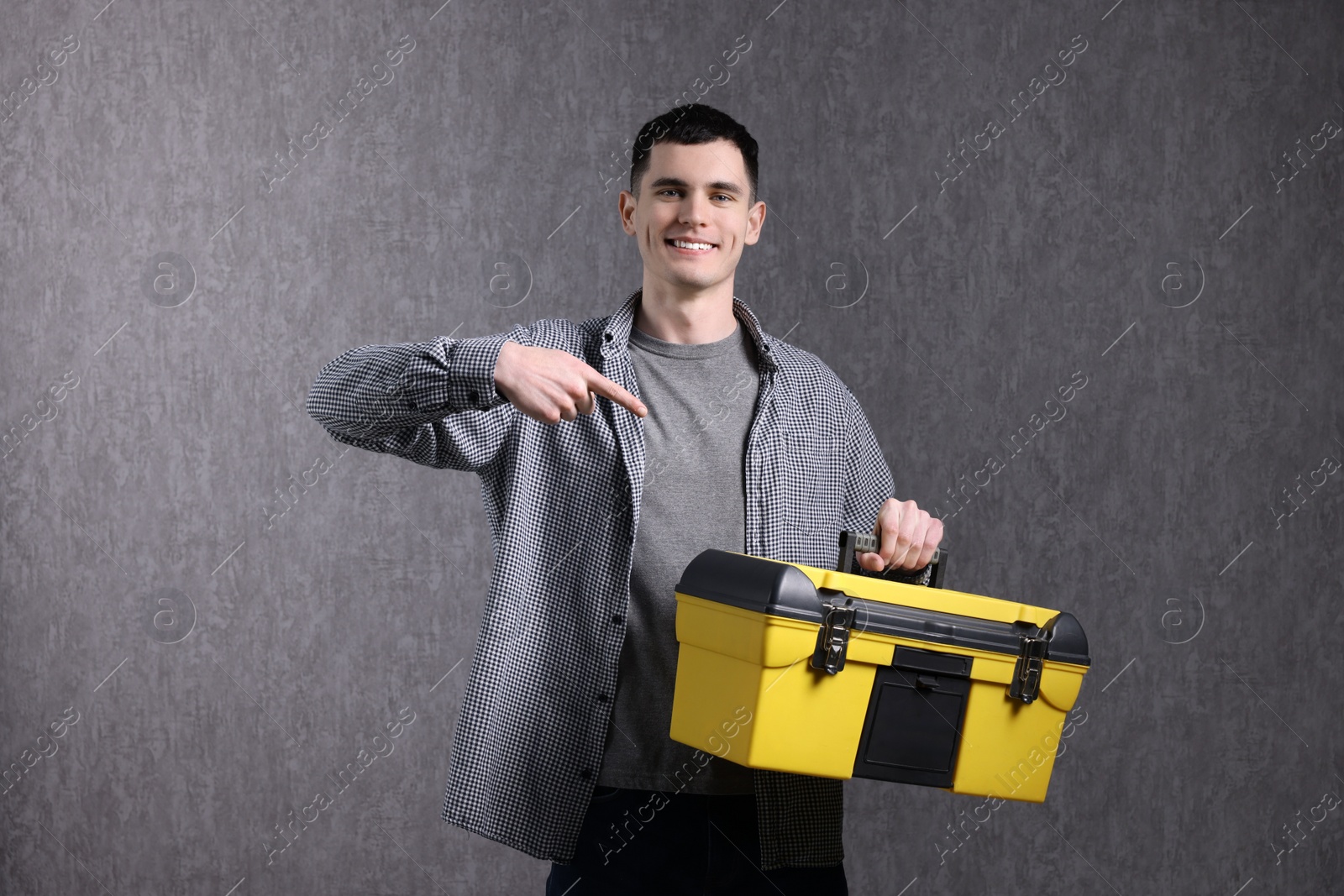 Photo of Young man with tool box on grey background