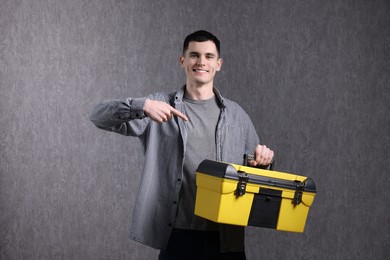 Young man with tool box on grey background