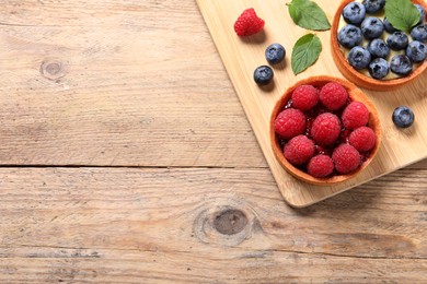 Tartlets with different fresh berries on wooden table, top view and space for text. Delicious dessert