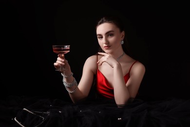 Photo of Fashionable photo of attractive young woman with glass of wine on black background