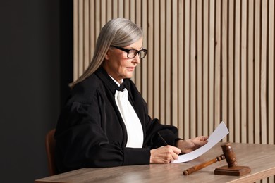 Photo of Judge in court dress working with document indoors