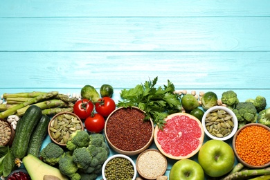 Photo of Fresh vegetables, fruits and seeds on light blue wooden table, flat lay. Space for text