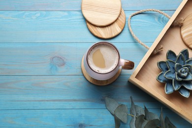 Photo of Mug of coffee, tray and stylish cup coasters on turquoise wooden table, flat lay. Space for text