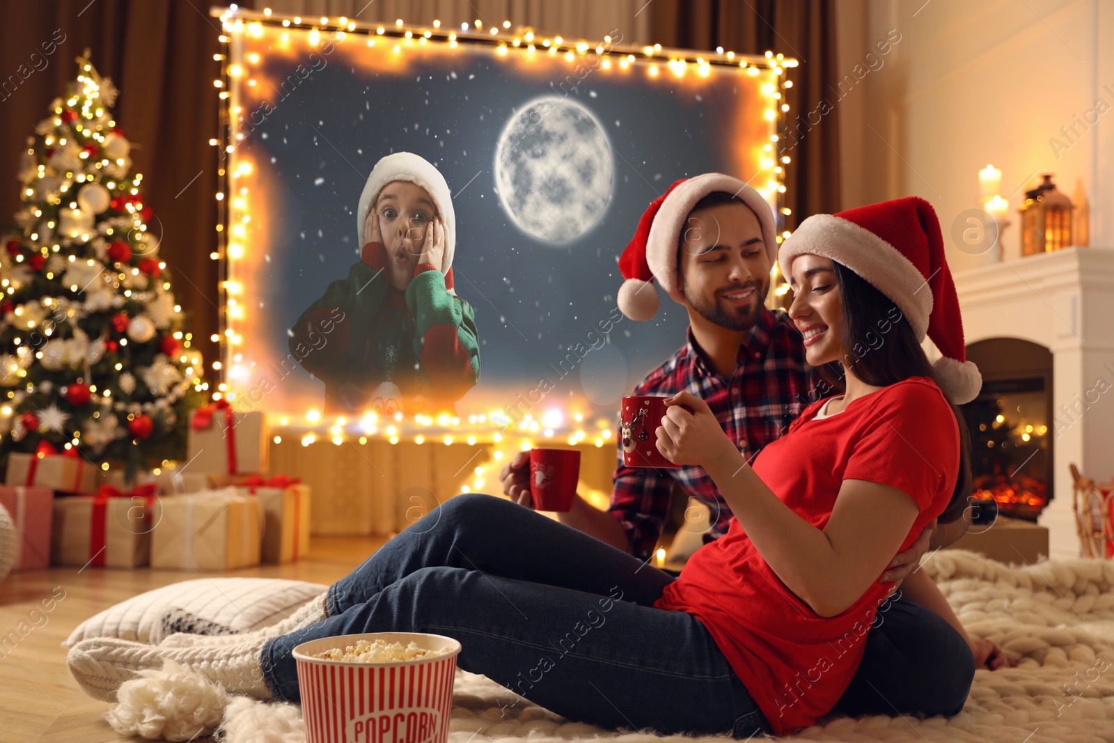 Image of Couple watching movie on projection screen in room decorated for Christmas