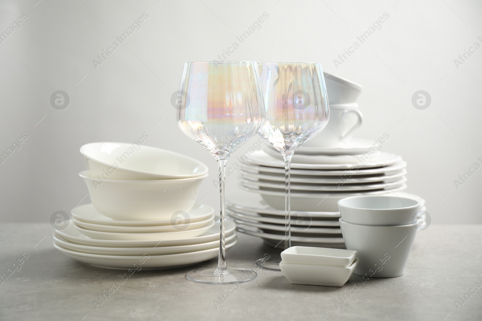 Photo of Set of clean dishes and glasses on light grey table