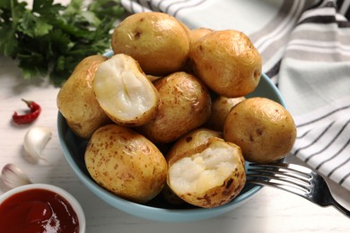 Photo of Bowl of tasty whole baked potatoes and sauce on white table, closeup