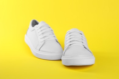 Photo of Pair of stylish white sneakers on yellow background