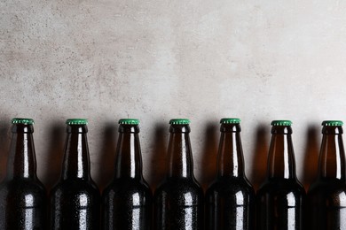 Glass bottles of beer on light grey background, flat lay. Space for text