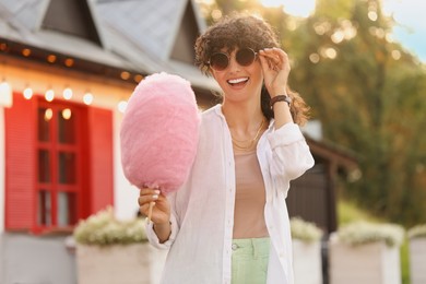 Photo of Portrait of smiling woman with cotton candy outdoors on sunny day