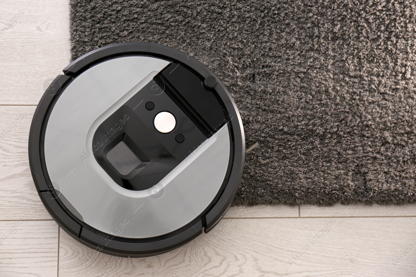Photo of Modern robotic vacuum cleaner on dark carpet, top view. Space for text