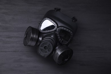 Photo of One gas mask on black wooden background, top view