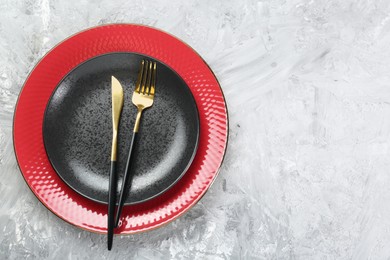 Photo of Clean plates and cutlery on gray textured table, top view. Space for text