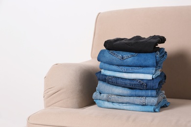 Photo of Stack of different jeans on sofa against white background