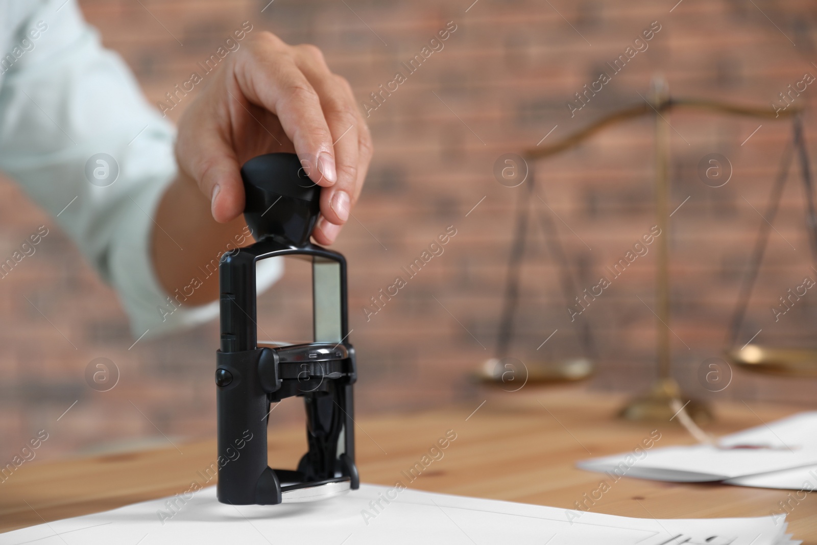 Photo of Male notary stamping document at table, closeup. Space for text