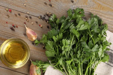 Bunch of raw parsley, oil, garlic and peppercorns on wooden table, flat lay