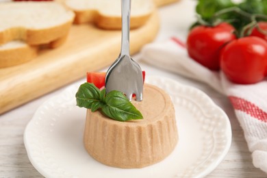 Delicious meat pate with basil and tomato served on white wooden table, closeup