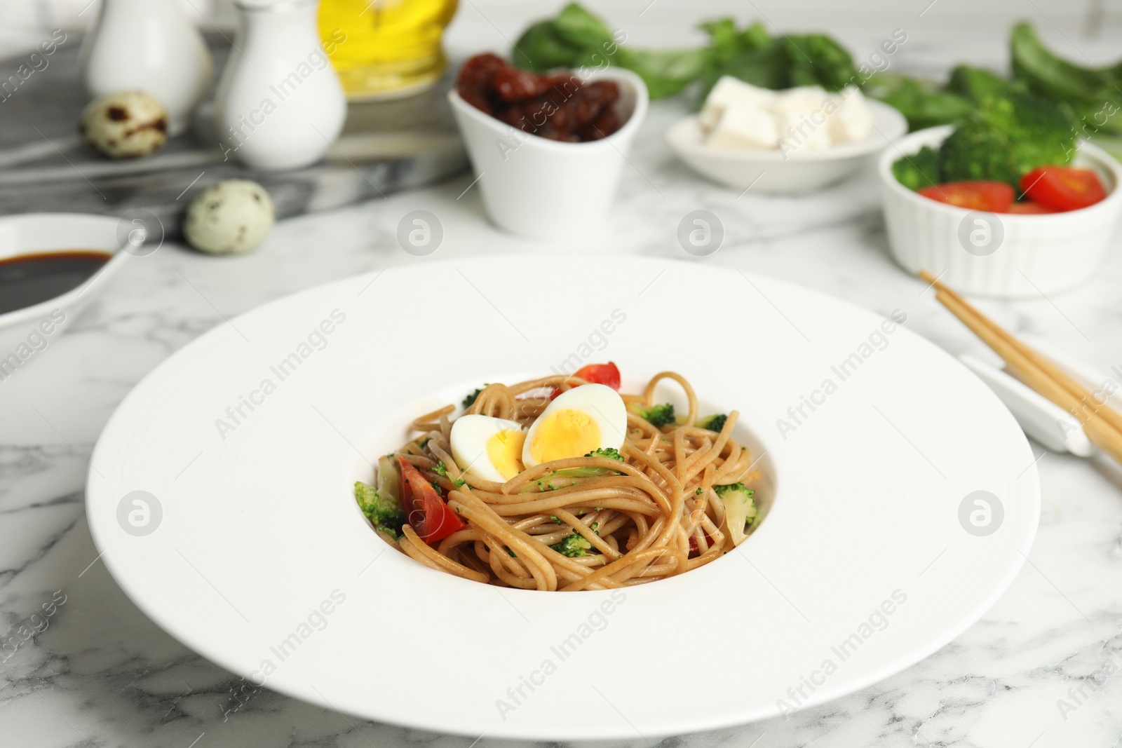 Photo of Tasty buckwheat noodles served on white marble table