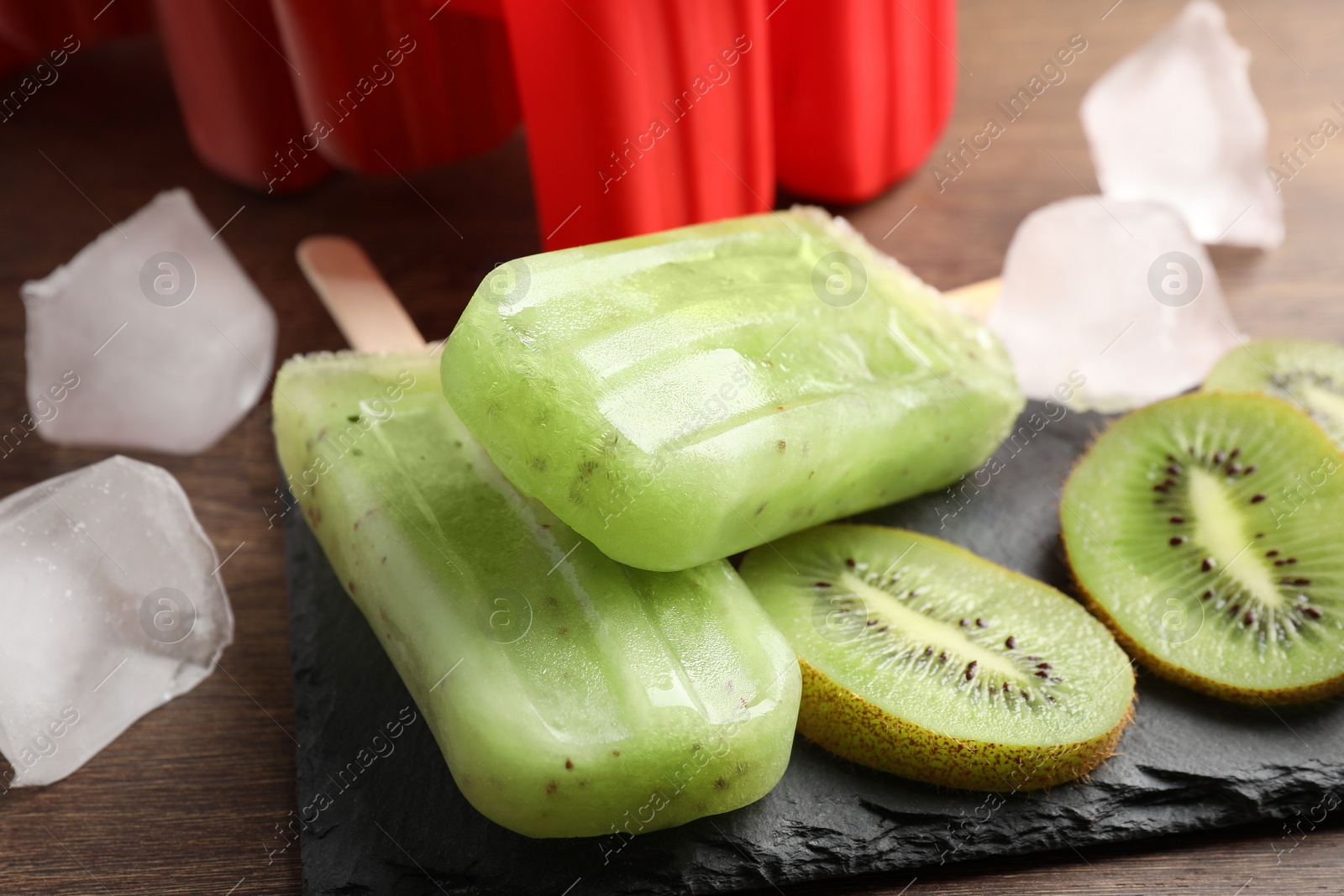 Photo of Tasty kiwi ice pops on wooden table, closeup. Fruit popsicle