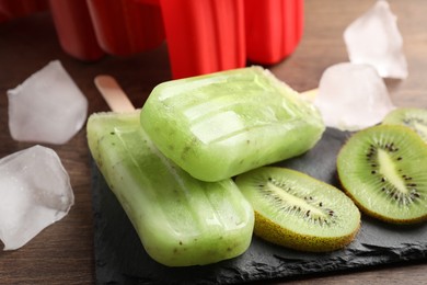 Tasty kiwi ice pops on wooden table, closeup. Fruit popsicle