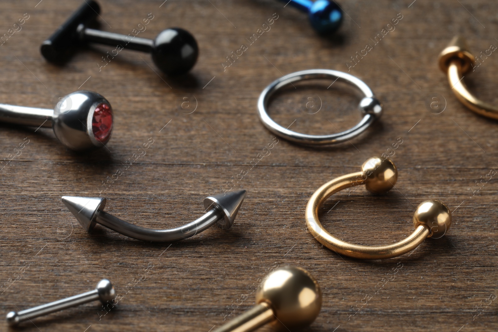 Photo of Stylish jewelry for piercing on wooden table, closeup