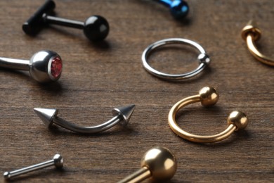 Photo of Stylish jewelry for piercing on wooden table, closeup