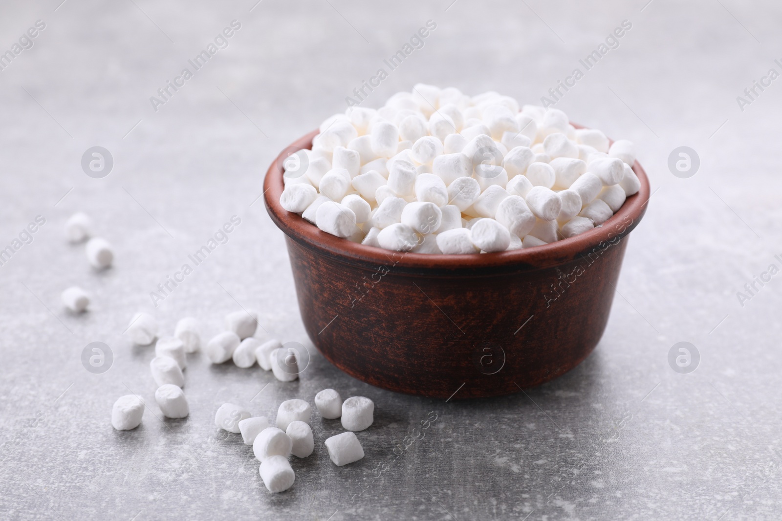 Photo of Bowl with delicious marshmallows on light gray background