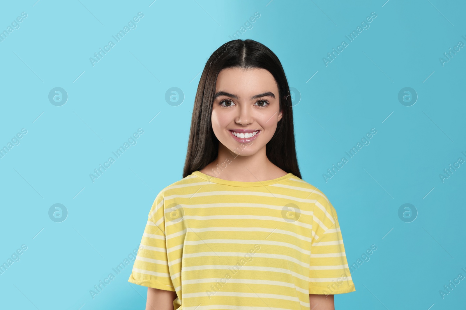 Photo of Portrait of happy teenage girl on light blue background