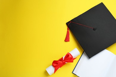 Photo of Graduation hat, book and diploma on yellow background, flat lay. Space for text