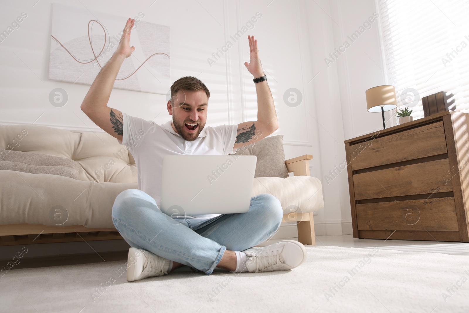 Photo of Emotional man participating in online auction using laptop at home