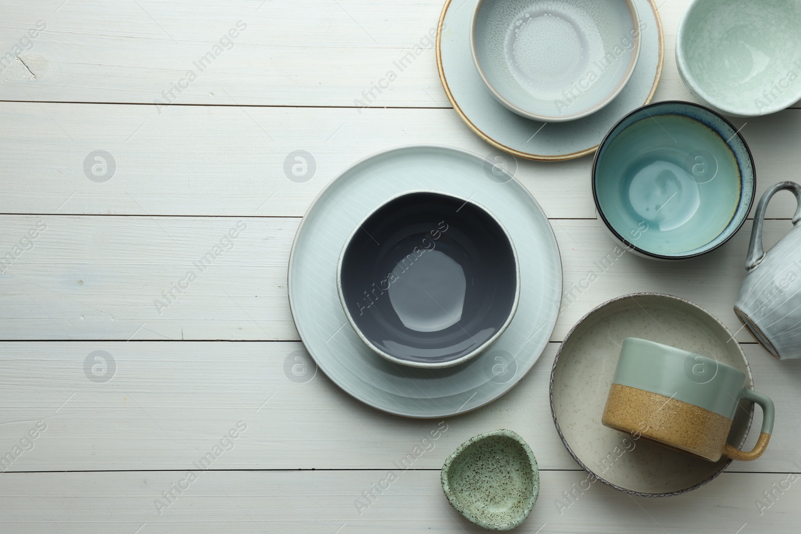 Photo of Stylish empty dishware on white wooden table, flat lay. Space for text