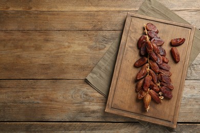 Photo of Sweet dried dates on wooden table, top view. Space for text