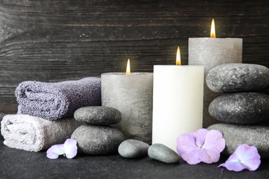 Photo of Composition with zen stones, towels and candles on table against wooden background