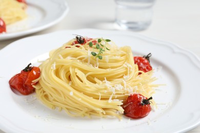 Photo of Tasty capellini with tomatoes and cheese served on table, closeup. Exquisite presentation of pasta dish