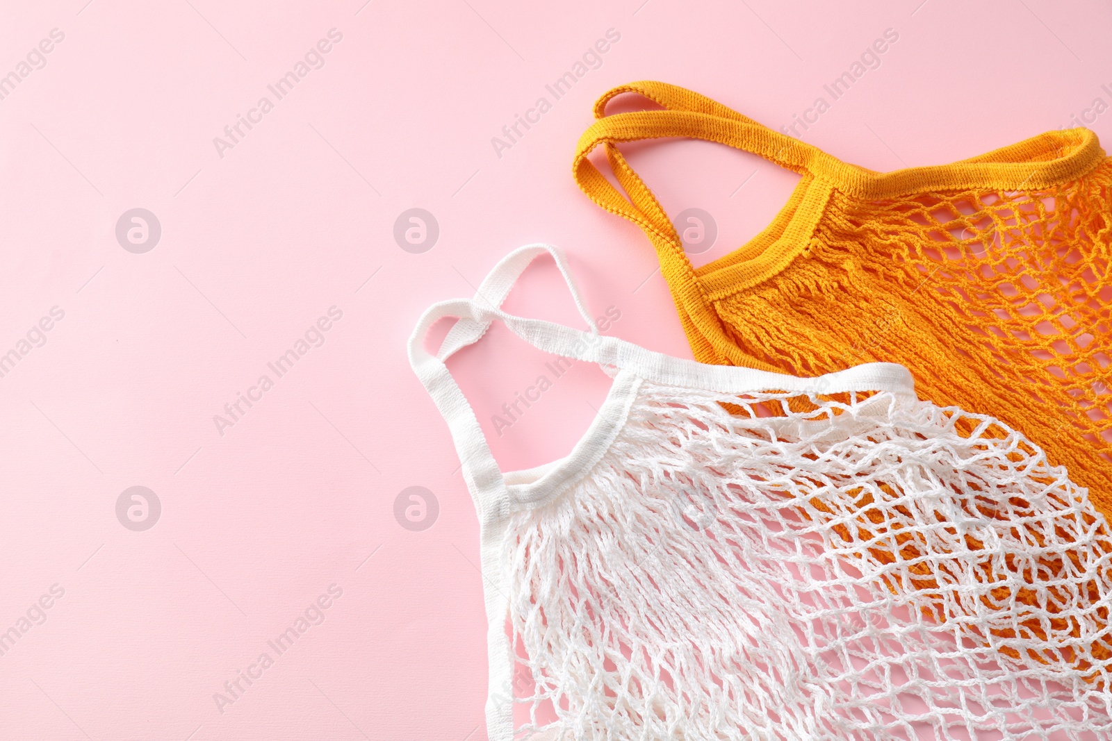 Photo of Orange and white string bag on pink background, top view. Space for text