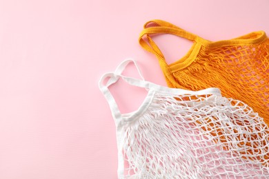 Photo of Orange and white string bag on pink background, top view. Space for text