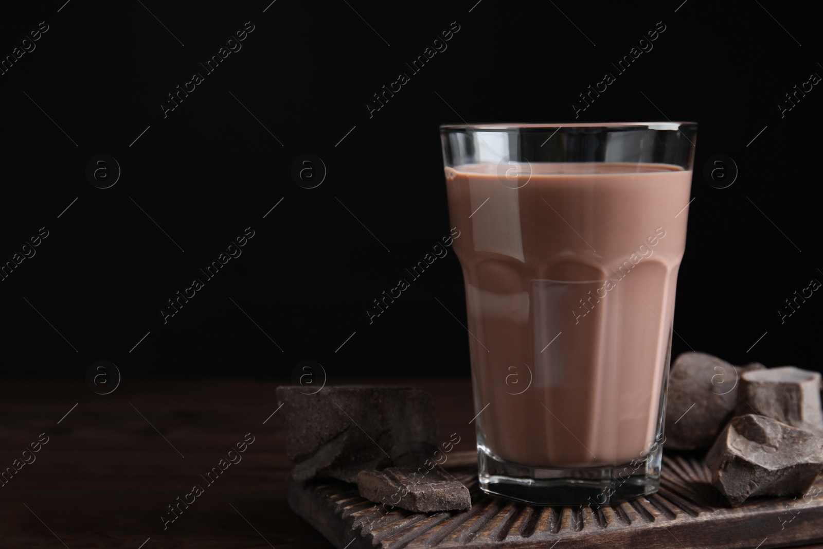 Photo of Fresh yummy chocolate milk on wooden table. Space for text