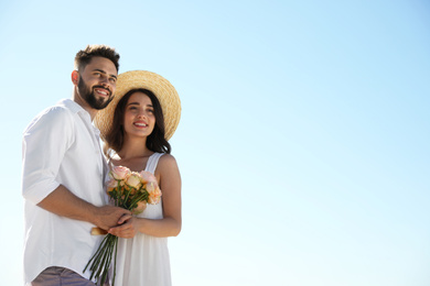 Photo of Happy young couple with flowers against blue sky. Honeymoon trip
