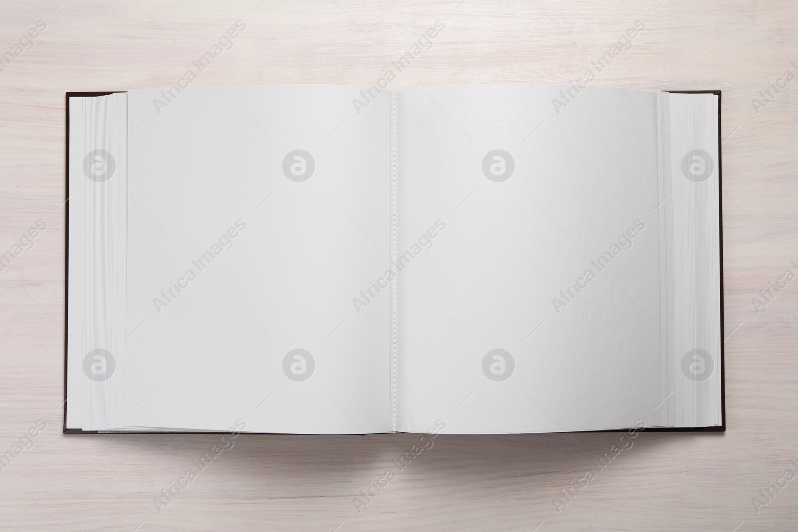 Photo of One open photo album on wooden table, top view