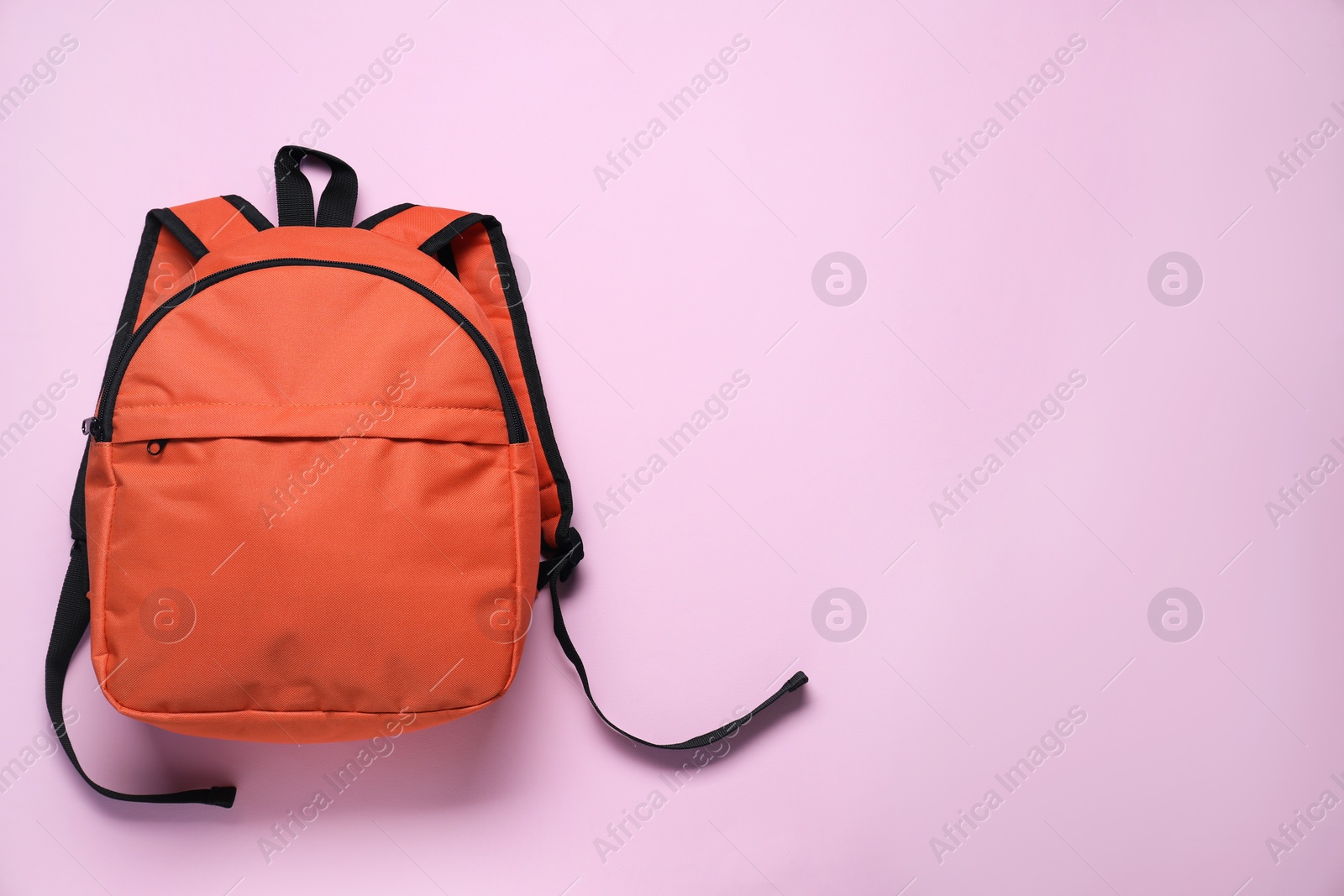 Photo of Stylish orange backpack on violet background, top view. Space for text