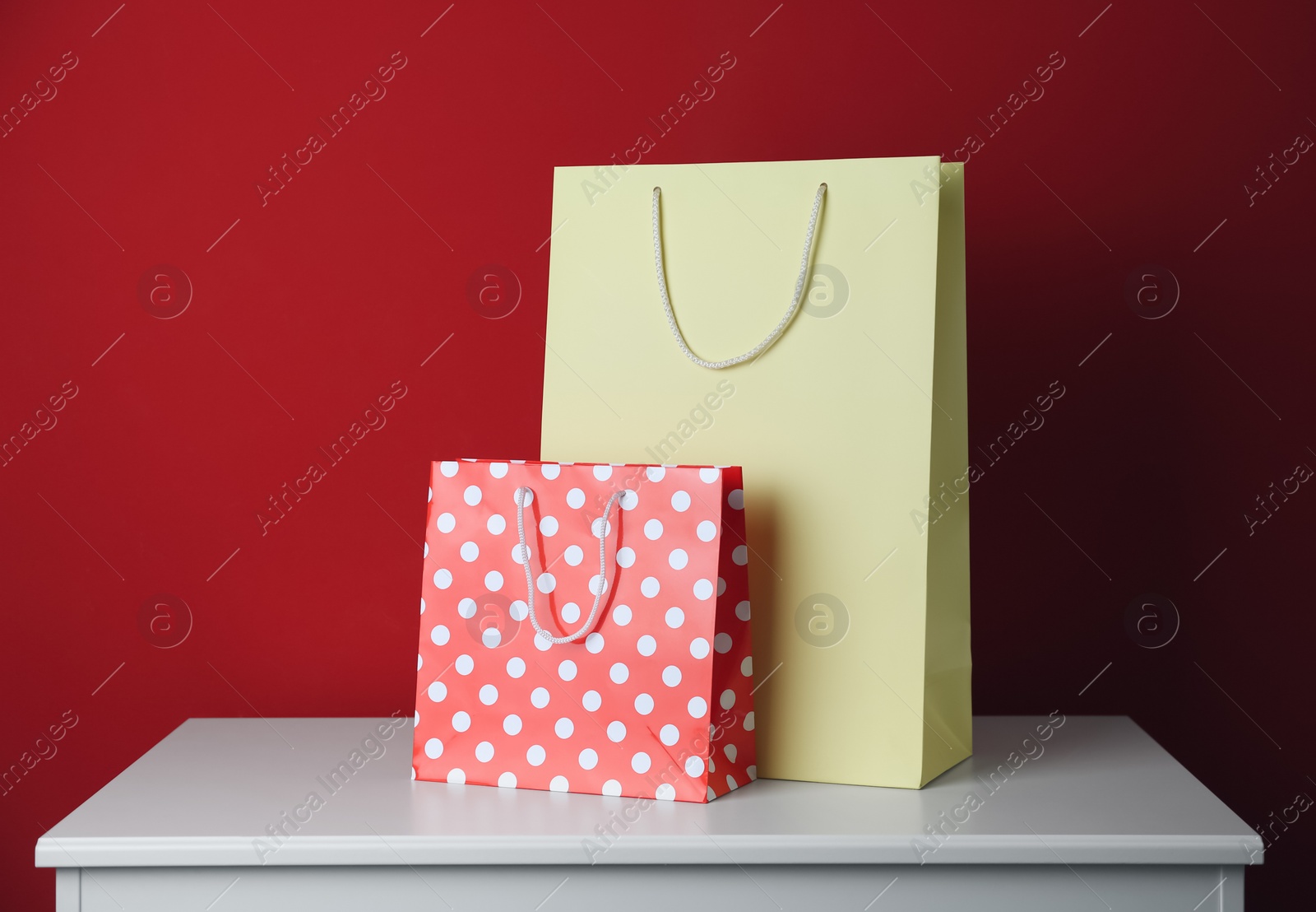 Photo of Paper shopping bags on white table against red background