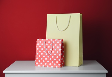 Paper shopping bags on white table against red background