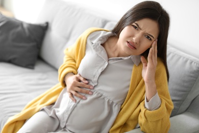 Young pregnant woman suffering from headache at home