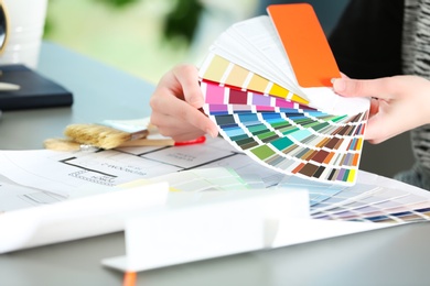 Photo of Female designer working with color palette samples at table