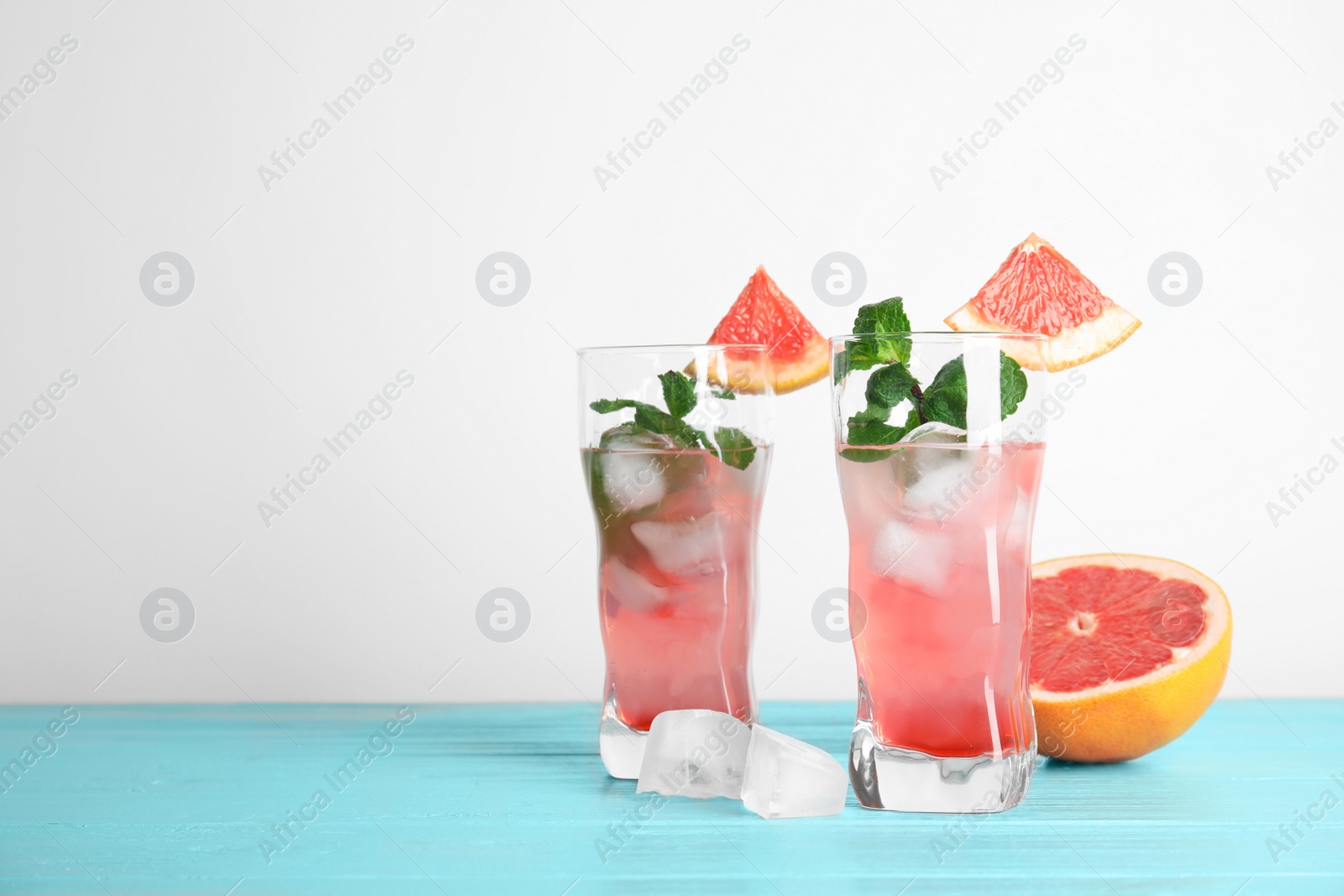 Photo of Glasses of cocktail and grapefruit half on table. Space for text