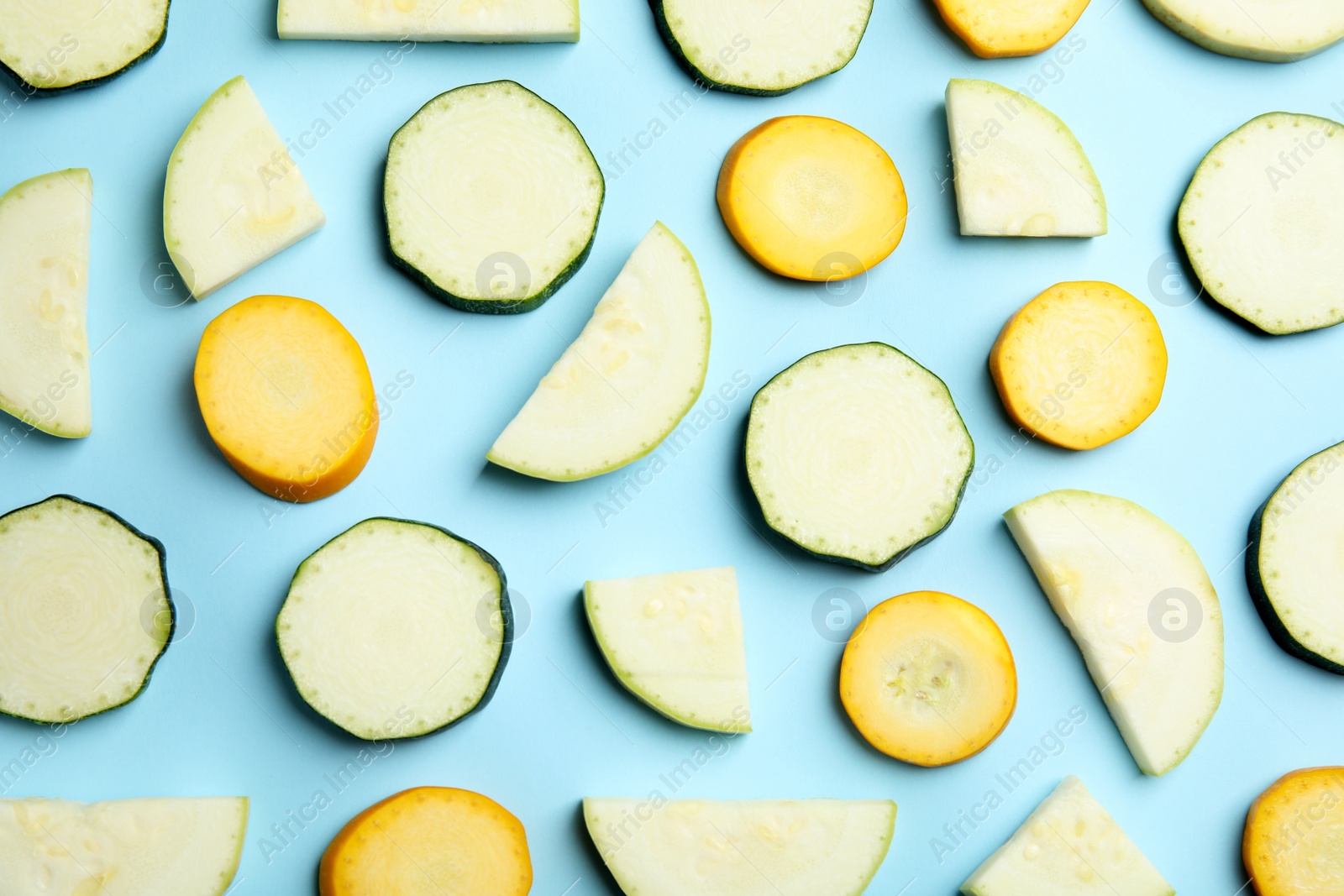 Photo of Fresh ripe cut zucchinis on light blue background, flat lay