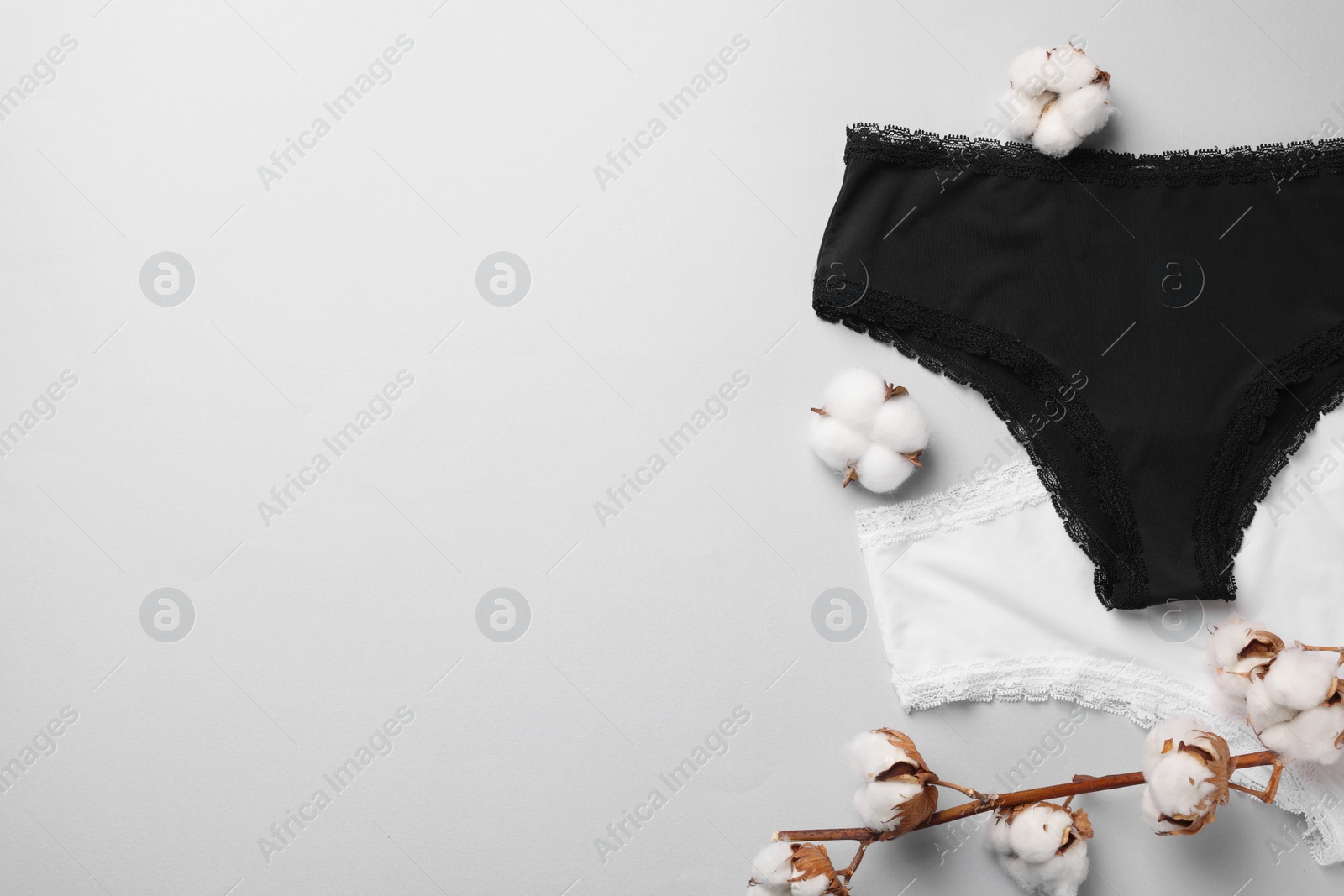 Photo of Women's underwear and cotton flowers on light grey background, flat lay. Space for text