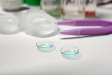 Contact lenses and tweezers on table, closeup