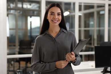 Photo of Smiling woman with clipboard in office. Lawyer, businesswoman, accountant or manager