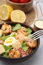 Photo of Delicious Caesar salad with shrimps and fork served on white table